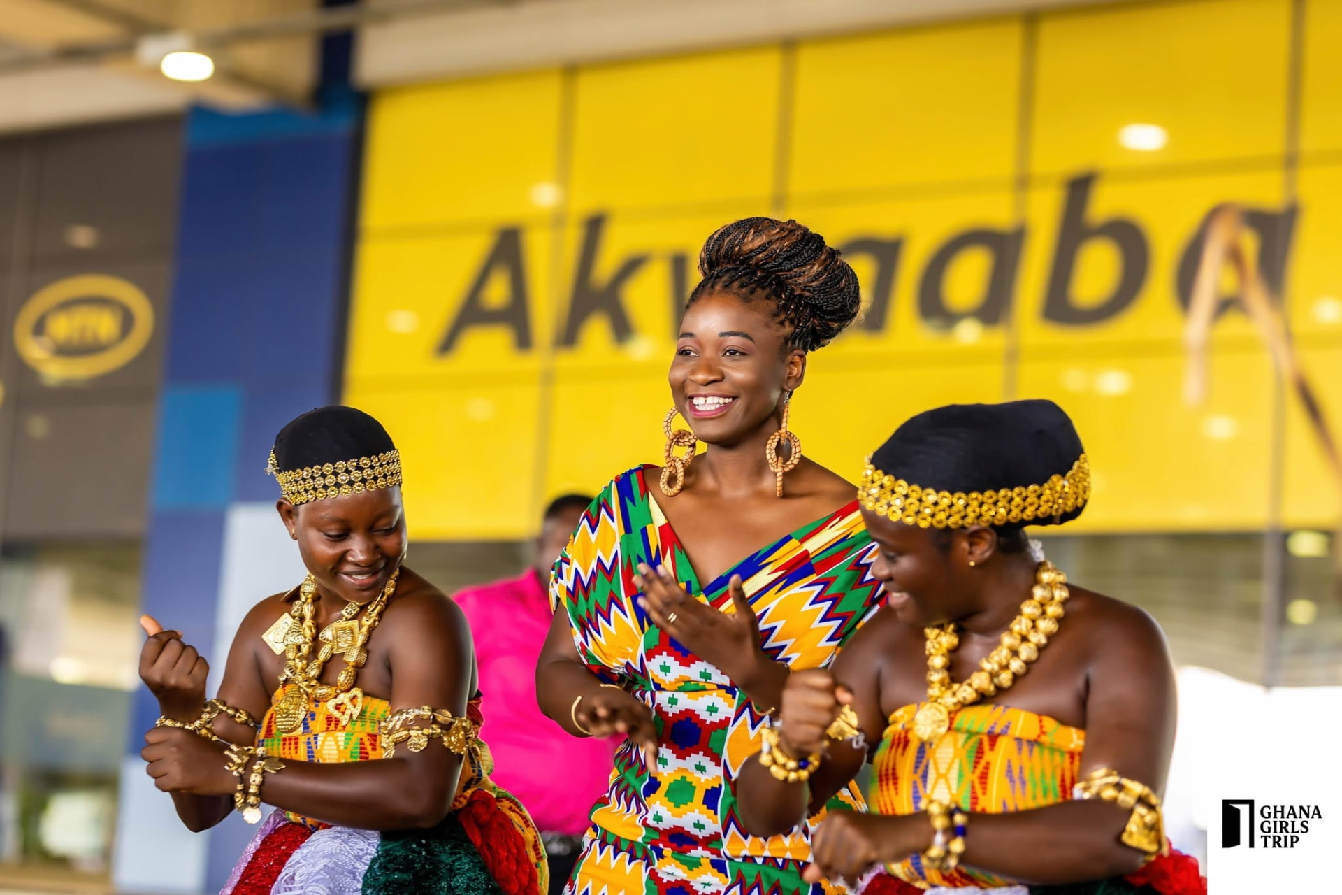 Naomi in traditional Ghanaian kente cloth with two children at an event